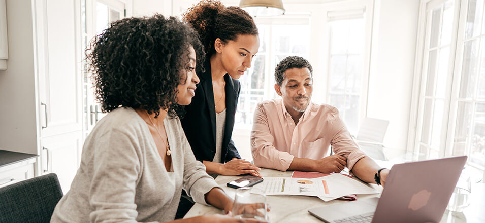 Young woman with parents at the counter looking over financial papers. 