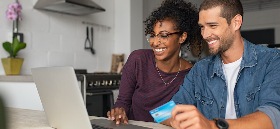 Man and woman with credit card looking at computer. 