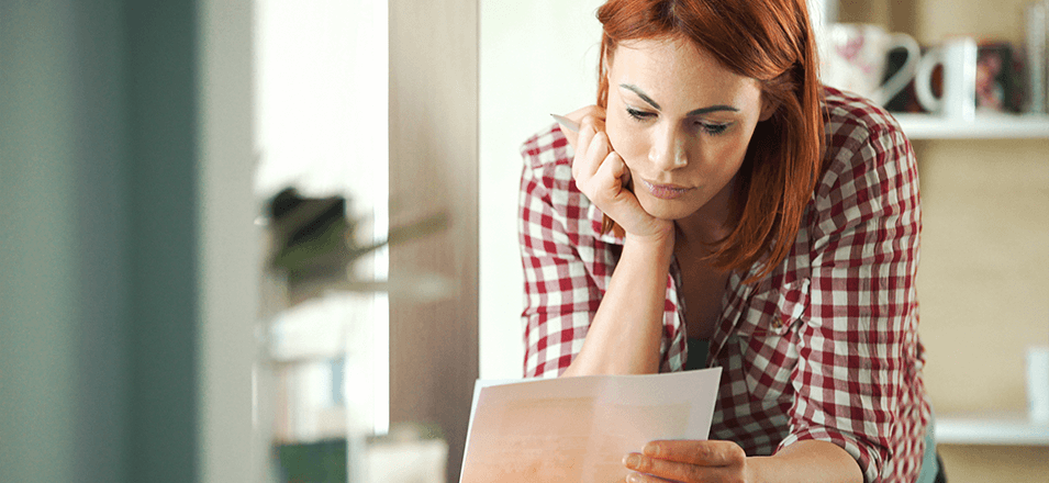 Young woman looking at papers while standing at counter