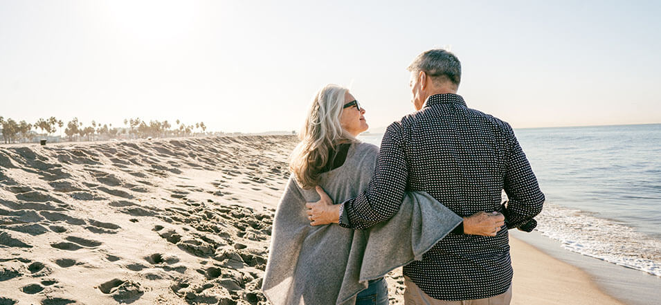 retired couple walking on beach