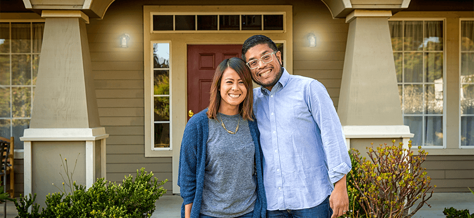 happy couple standing in front of house