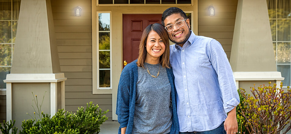 asian couple in front of their new home