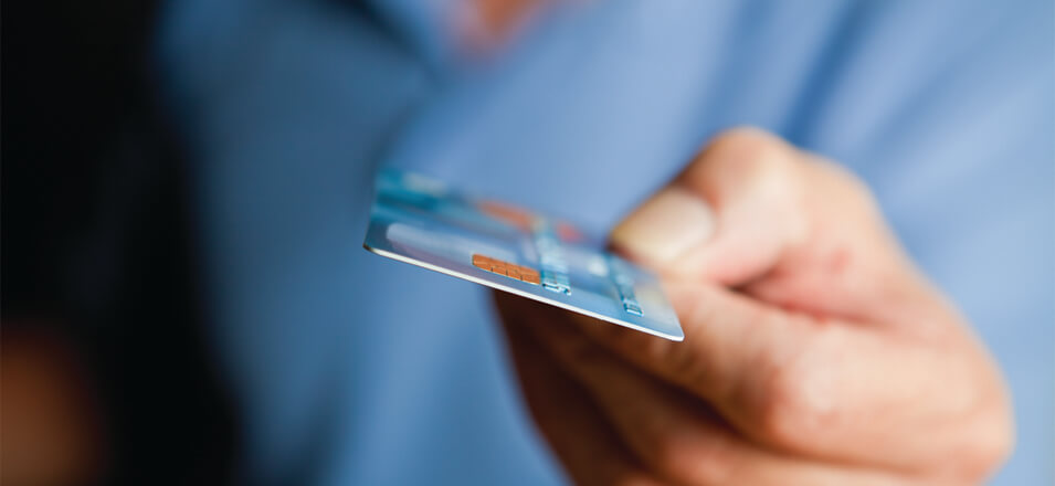 Person wearing blue shirt holding out a credit card
