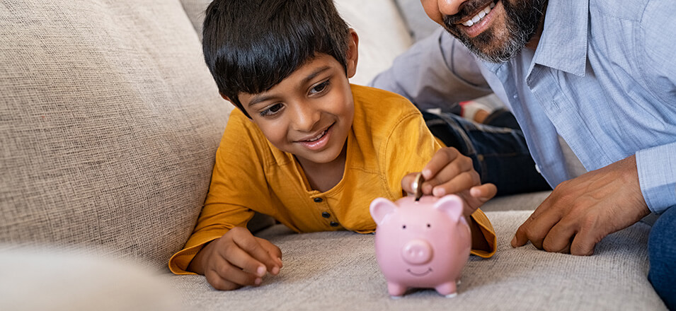 Dad and son adding change into piggy bank