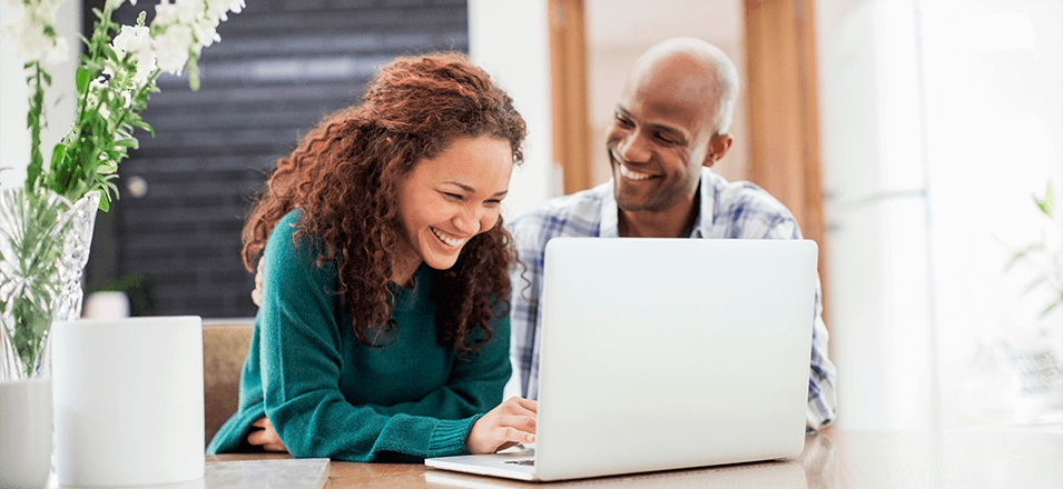 Happy couple sitting at laptop