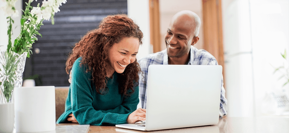 Happy couple sitting at laptop 