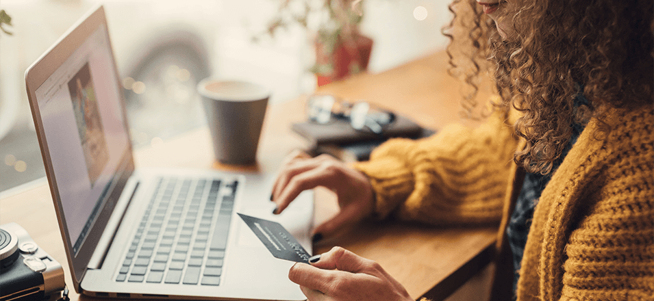 young woman sitting at computer with credit card in her hand 