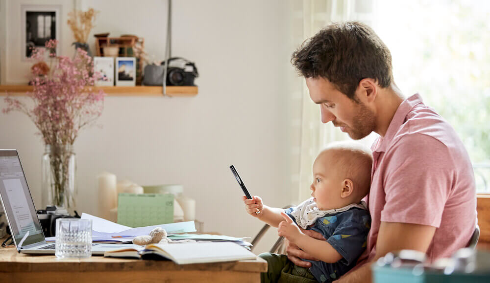 Man and baby at a table in front of a laptop