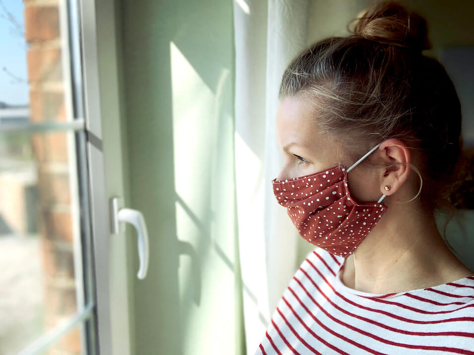 Woman in face mask looking out window