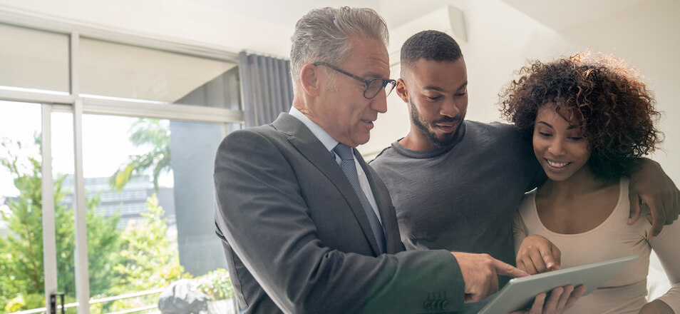 Real estate agent showing tablet to man and woman.