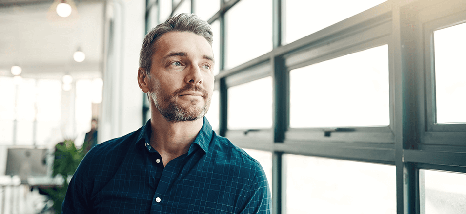 man sitting in room looking out industrial window